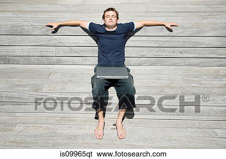 Man lying on decking with laptop View Large Photo Image Stock Photograph - Man lying on decking with laptop. Fotosearch