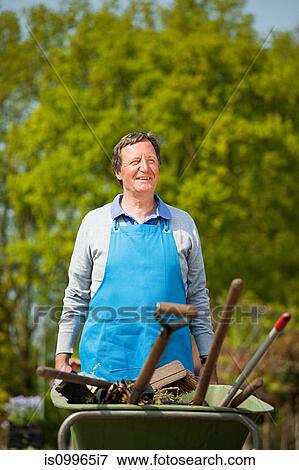 Man pushing wheelbarrow in plant nursery View Large Photo Image Stock Photo - Man pushing wheelbarrow in plant nursery. Fotosearch