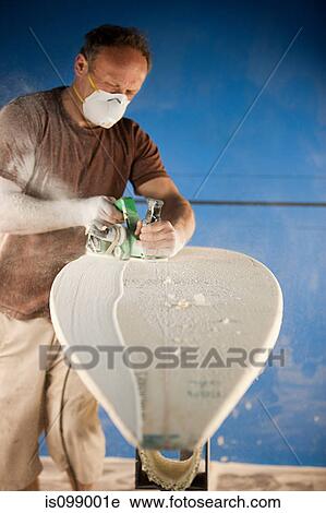 Stock Image - Man sanding surfboard. Fotosearch
