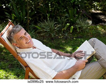 Man sitting on deckchair in garden with book View Large Photo Image Stock Photography - Man sitting on deckchair in garden with book. Fotosearch