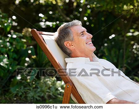 Man sitting on deckchair, portrait View Large Photo Image Stock Photograph - Man sitting on deckchair, portrait. Fotosearch