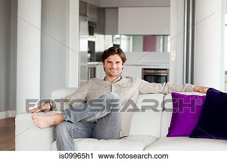 Stock Image - Man sitting on sofa, portrait. Fotosearch