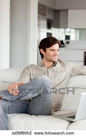 Stock Image - Man sitting on sofa, portrait. Fotosearch