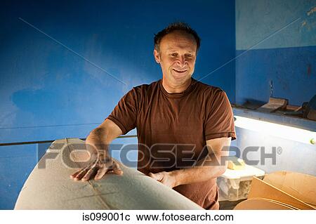 Stock Image - Man touching surfboard. Fotosearch