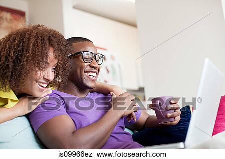 Stock Photo - Man using laptop woman looking over his shoulder. Fotosearch