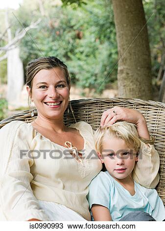 Mother and son sitting on wicker chair, portrait View Large Photo Image Stock Image - Mother and son sitting on wicker chair, portrait. Fotosearch