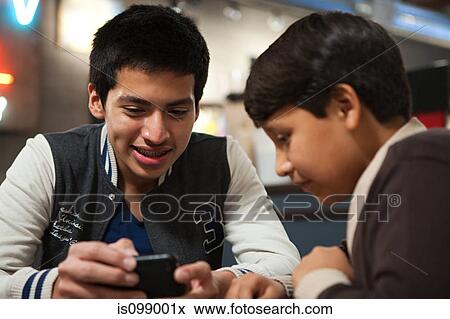 Stock Photo - Two brothers with smartphone in cafe. Fotosearch