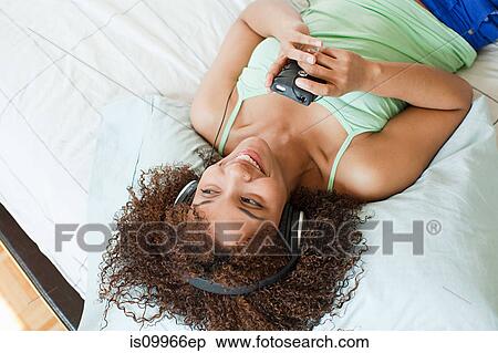 Woman listening to music, texting on smartphone View Large Photo Image Stock Photography - Woman listening to music, texting on smartphone. Fotosearch