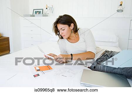 Woman on bed organising home finances View Large Photo Image Stock Photo - Woman on bed organising home finances. Fotosearch