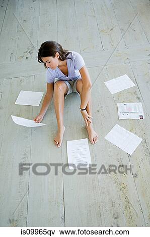 Stock Photo - Woman sitting on decking with financial documents. Fotosearch