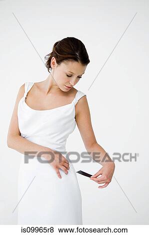 Stock Photo - Woman wearing white dress looking at price tag. Fotosearch