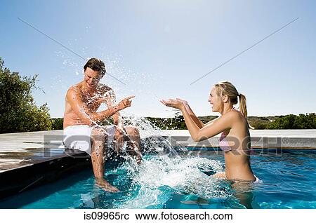 Young couple splashing in swimming pool View Large Photo Image Stock Image - Young couple splashing in swimming pool. Fotosearch