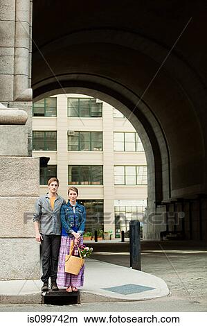 Young couple standing on city sidewalk View Large Photo Image Picture - Young couple standing on city sidewalk. Fotosearch
