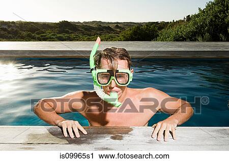 Stock Image - Young man wearing snorkel at poolside. Fotosearch