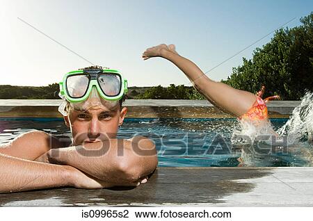 Young man wearing snorkel at poolside, woman diving in View Large Photo Image Stock Image - Young man wearing snorkel at poolside, woman diving in. Fotosearch