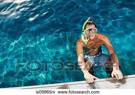 Stock Photograph - Young man wearing snorkel at poolside, high angle. Fotosearch