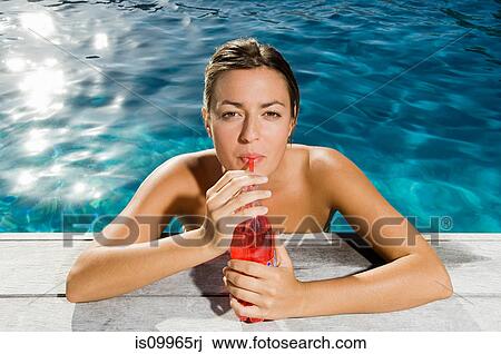 Young woman drinking soft drink at poolside View Large Photo Image Stock Image - Young woman drinking soft drink at poolside. Fotosearch