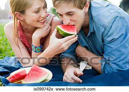Stock Photo - Young woman feeding man watermelon. Fotosearch
