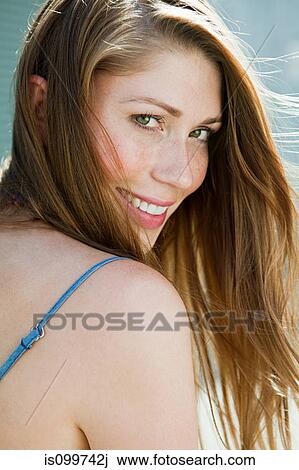 Young woman looking over shoulder, smiling View Large Photo Image Stock Image - Young woman looking over shoulder, smiling. Fotosearch