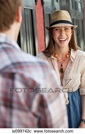 Stock Image - Young woman smiling at man outdoors. Fotosearch