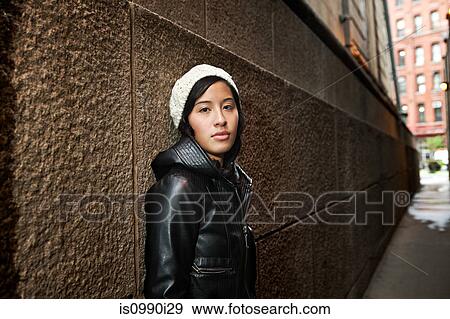 Stock Photo - Young woman wearing knit hat by wall. Fotosearch