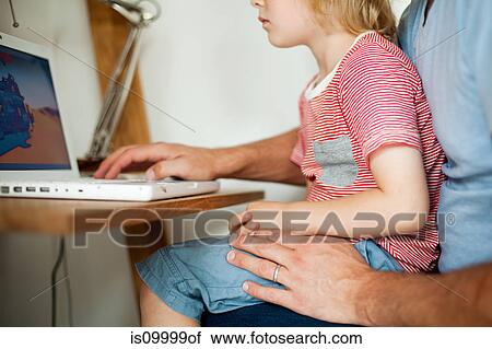 Boy sitting on father's lap at computer desk View Large Photo Image Stock Image - Boy sitting on father's lap at computer desk. Fotosearch