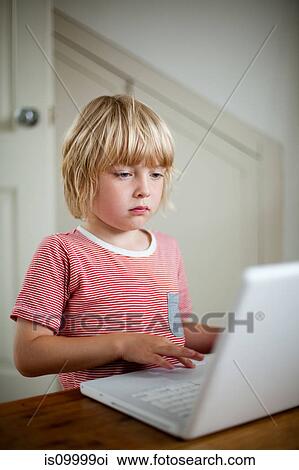 Boy using laptop on desk View Large Photo Image Stock Image - Boy using laptop on desk. Fotosearch
