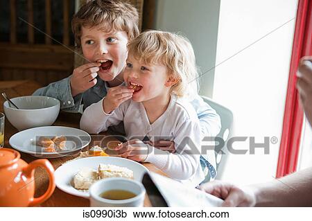 Stock Image - Brother and sister having breakfast. Fotosearch