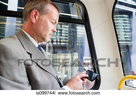 Stock Image - Businessman using smartphone on bus. Fotosearch