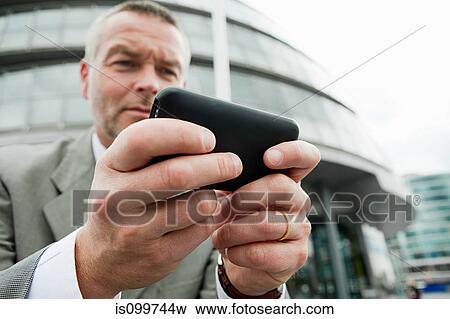 Stock Photo - Businessman using smartphone outdoors. Fotosearch