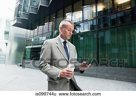 Businessman walking with smartphone and coffee View Large Photo Image Stock Photograph - Businessman walking with smartphone and coffee. Fotosearch