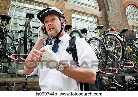 Businessman wearing cycling helmet and using cellphone View Large Photo Image Stock Photography - Businessman wearing cycling helmet and using cellphone. Fotosearch