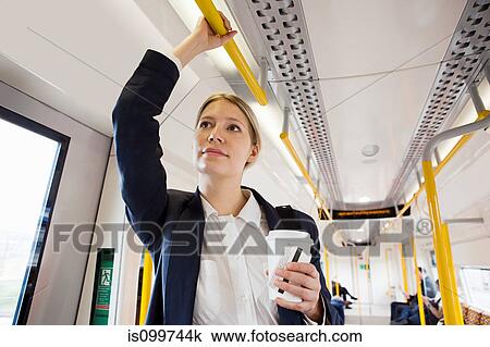 Stock Image - Businesswoman travelling on London Overground train. Fotosearch
