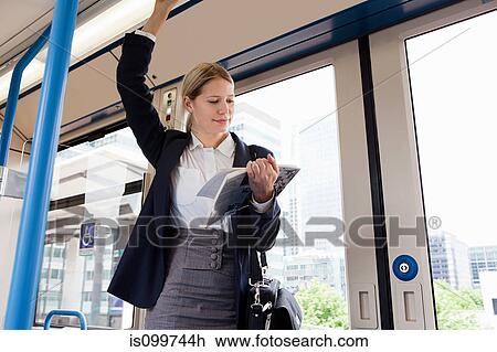 Stock Image - Businesswoman travelling on train with book. Fotosearch