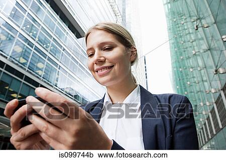 Businesswoman using smartphone amongst office buildings View Large Photo Image Stock Image - Businesswoman using smartphone amongst office buildings. Fotosearch