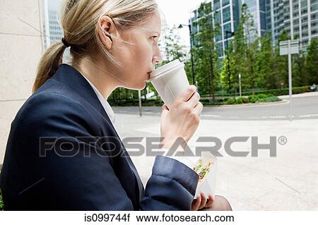 Stock Image - Businesswoman with coffee and sandwiches. Fotosearch