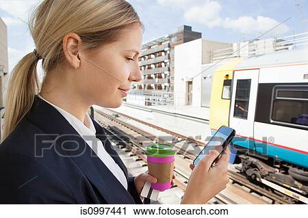 Businesswoman with coffee and smart phone in train station View Large Photo Image Stock Image - Businesswoman with coffee and smart phone in train station. Fotosearch