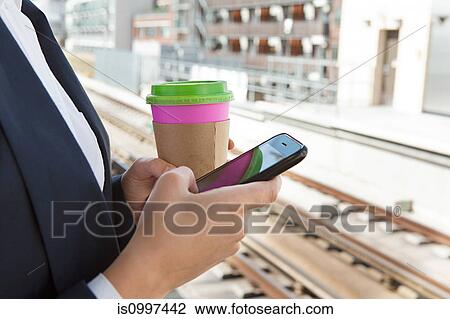 Close up of woman with coffee and smart phone in train station View Large Photo Image Stock Image - Close up of woman with coffee and smart phone in train station. Fotosearch