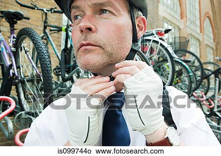 Cyclist putting on cycling helmet View Large Photo Image Picture - Cyclist putting on cycling helmet. Fotosearch