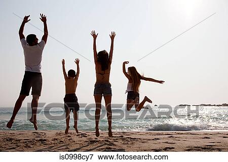 Stock Photo - Family jumping up in the air on a beach. Fotosearch
