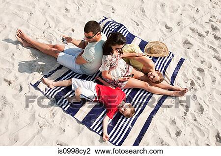 Family sitting and lying together on a rug on a beach View Large Photo Image Stock Image - Family sitting and lying together on a rug on a beach. Fotosearch