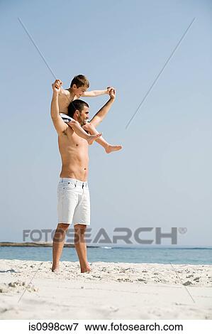 Father carrying son on his shoulders on a beach View Large Photo Image Stock Photo - Father carrying son on his shoulders on a beach. Fotosearch