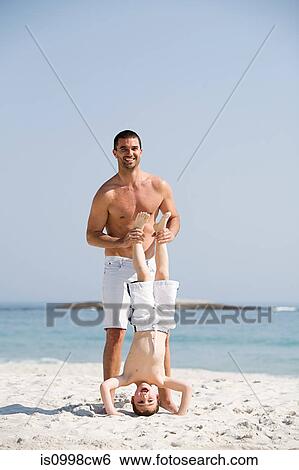 Father holding son in a headstand position on a beach View Large Photo Image Stock Photograph - Father holding son in a headstand position on a beach. Fotosearch
