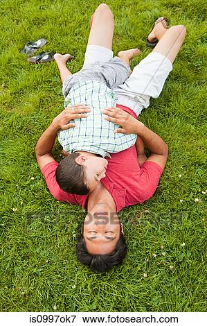 Stock Photo - Father lying on grass with son. Fotosearch