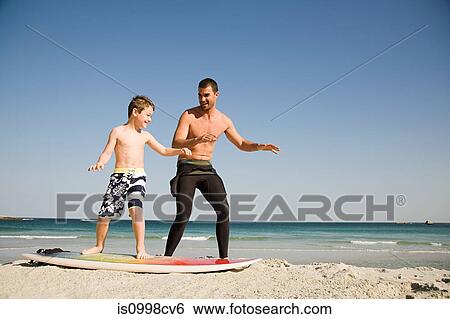 Father teaching son how to surf View Large Photo Image Stock Photograph - Father teaching son how to surf. Fotosearch