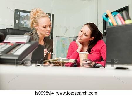 Female colleagues discussing work together View Large Photo Image Picture - Female colleagues discussing work together. Fotosearch