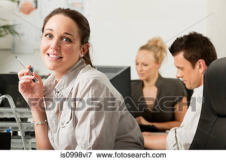 Female employee holding a biro and smiling View Large Photo Image Stock Photo - Female employee holding a biro and smiling. Fotosearch