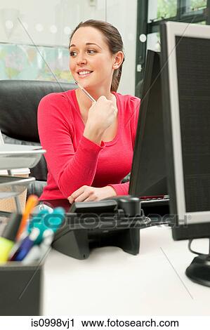 Stock Image - Female employee sitting at her computer. Fotosearch