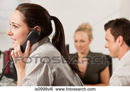Female employee using a telephone in the office View Large Photo Image Stock Photograph - Female employee using a telephone in the office. Fotosearch