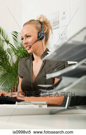 Female employee using handsfree device while typing View Large Photo Image Stock Photography - Female employee using handsfree device while typing. Fotosearch